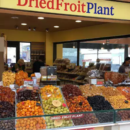 Outdoor farmer market stall with colorful canopy displaying fresh produce dried fruits and packaged goods for local customers